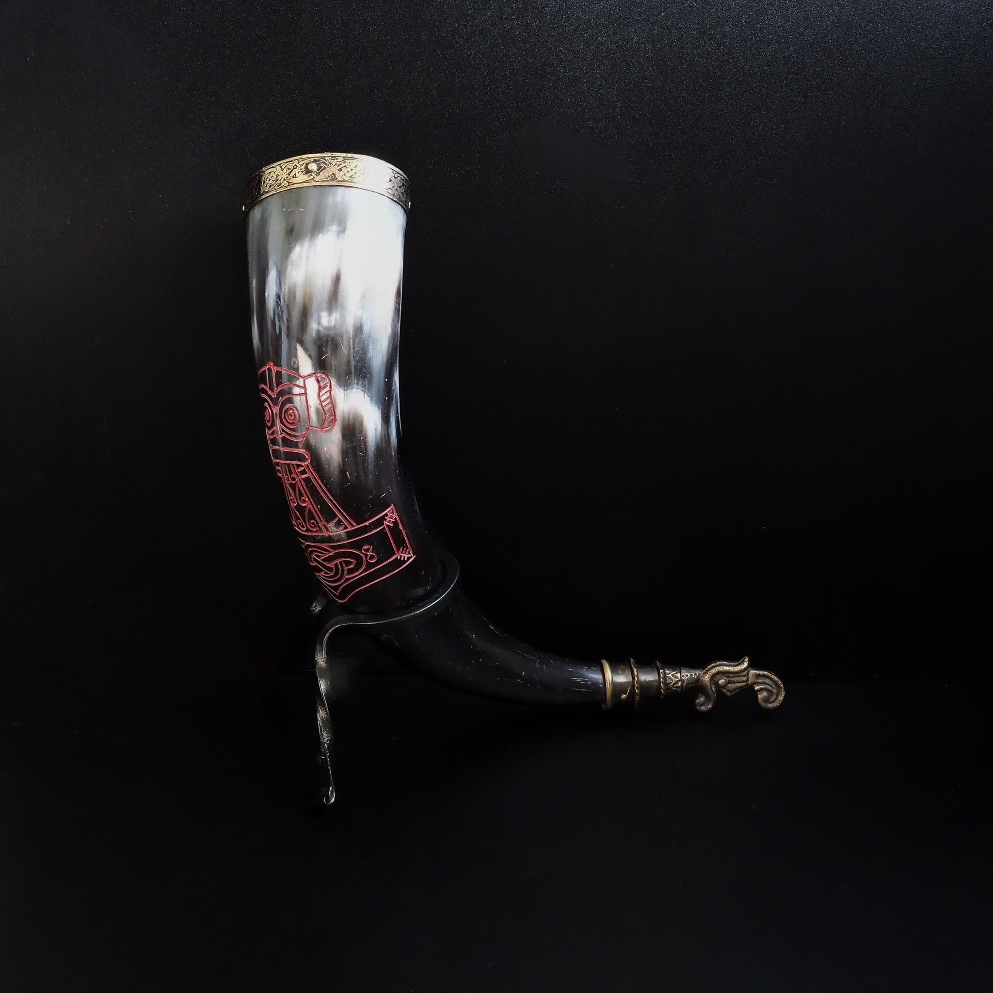 Dryckeshorn framifrån visar vikingmotiv i rött på creamfärgat horn. Korp-gravyr med geometriska monster under.