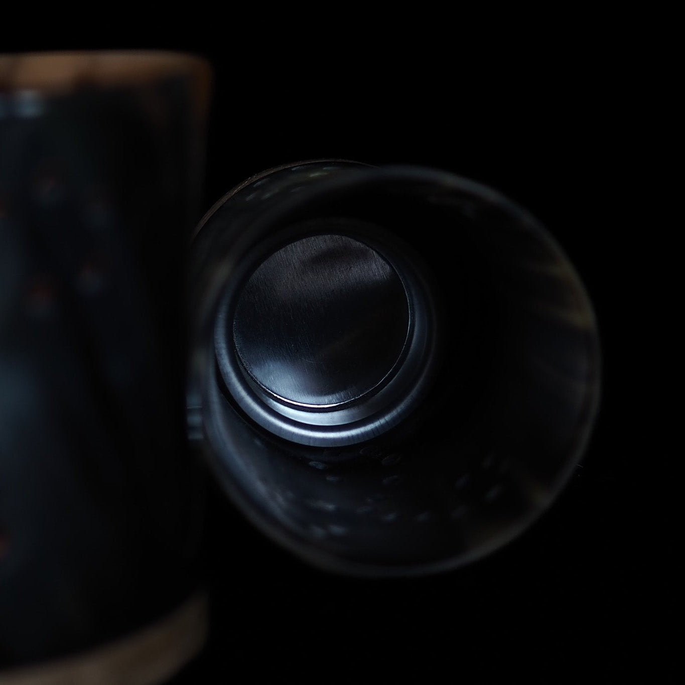 Mörk hornlykta ovanifrån visar insida med värmeljushållare mot svart bakgrund