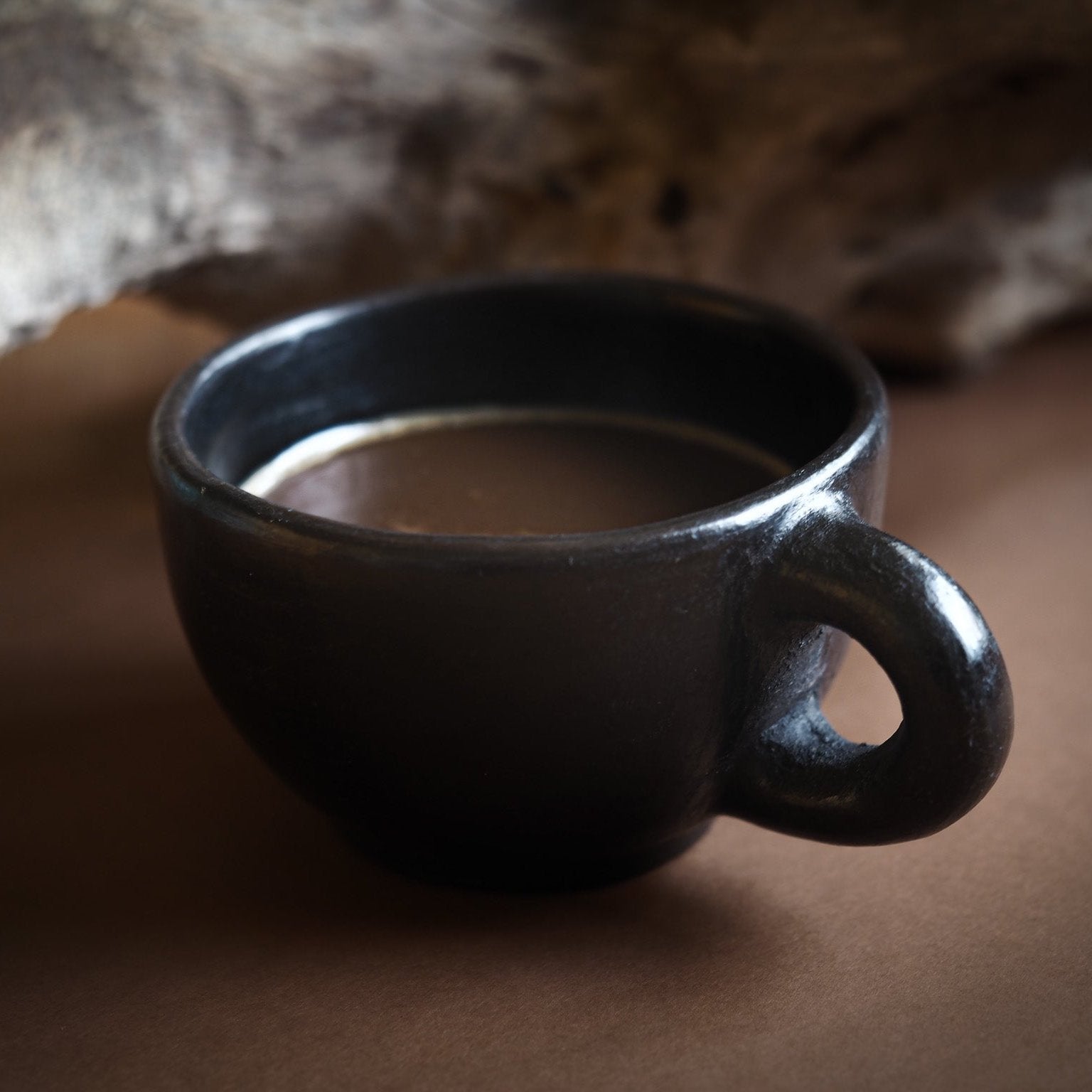Svart eldad lerkoppar med öra i Birka-inspirerad stil. Glänsande svart yta från milbränning. Rund form med robust handtag.