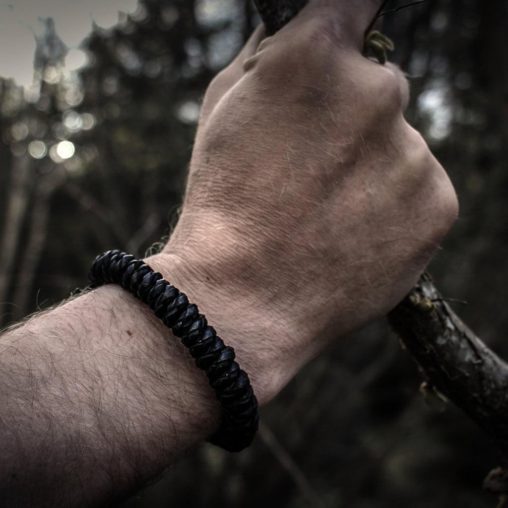 Lifestyle-foto av svart brokk-armband på en mans handled med skogsbakgrund. Visar hur armbandet sitter på handled.