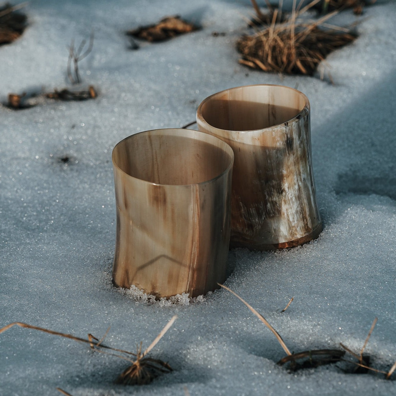 Två polerade hornlyktor i varma nyanser stående i snö utomhus